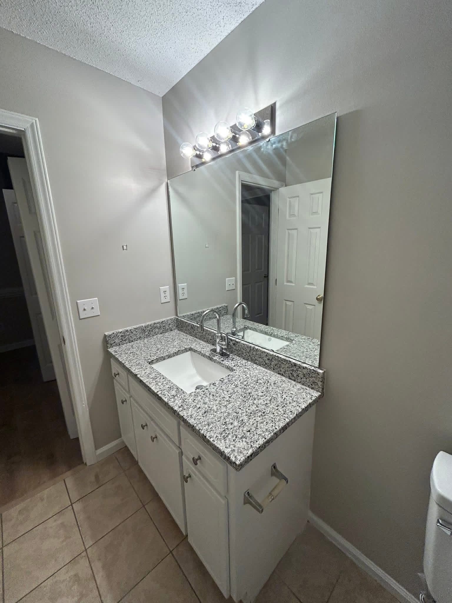 Bathroom vanity with painted white cabinets and granite countertop by Tacho Painting LLC