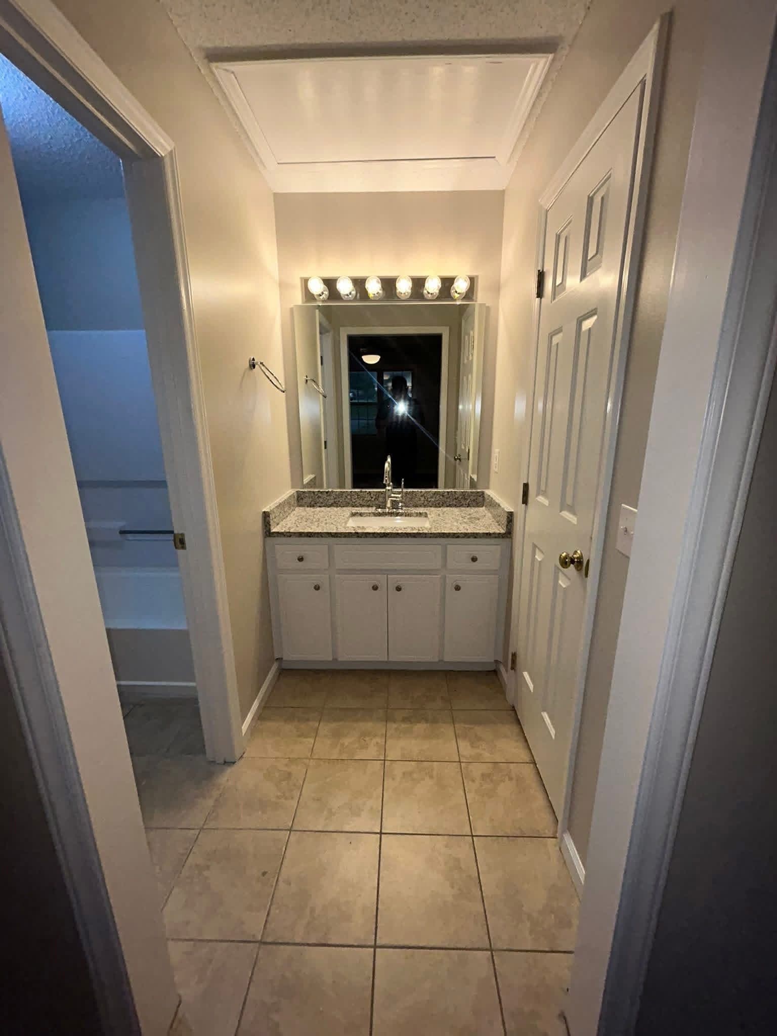 Bathroom hallway and vanity with freshly painted walls and white cabinets by Tacho Painting LLC