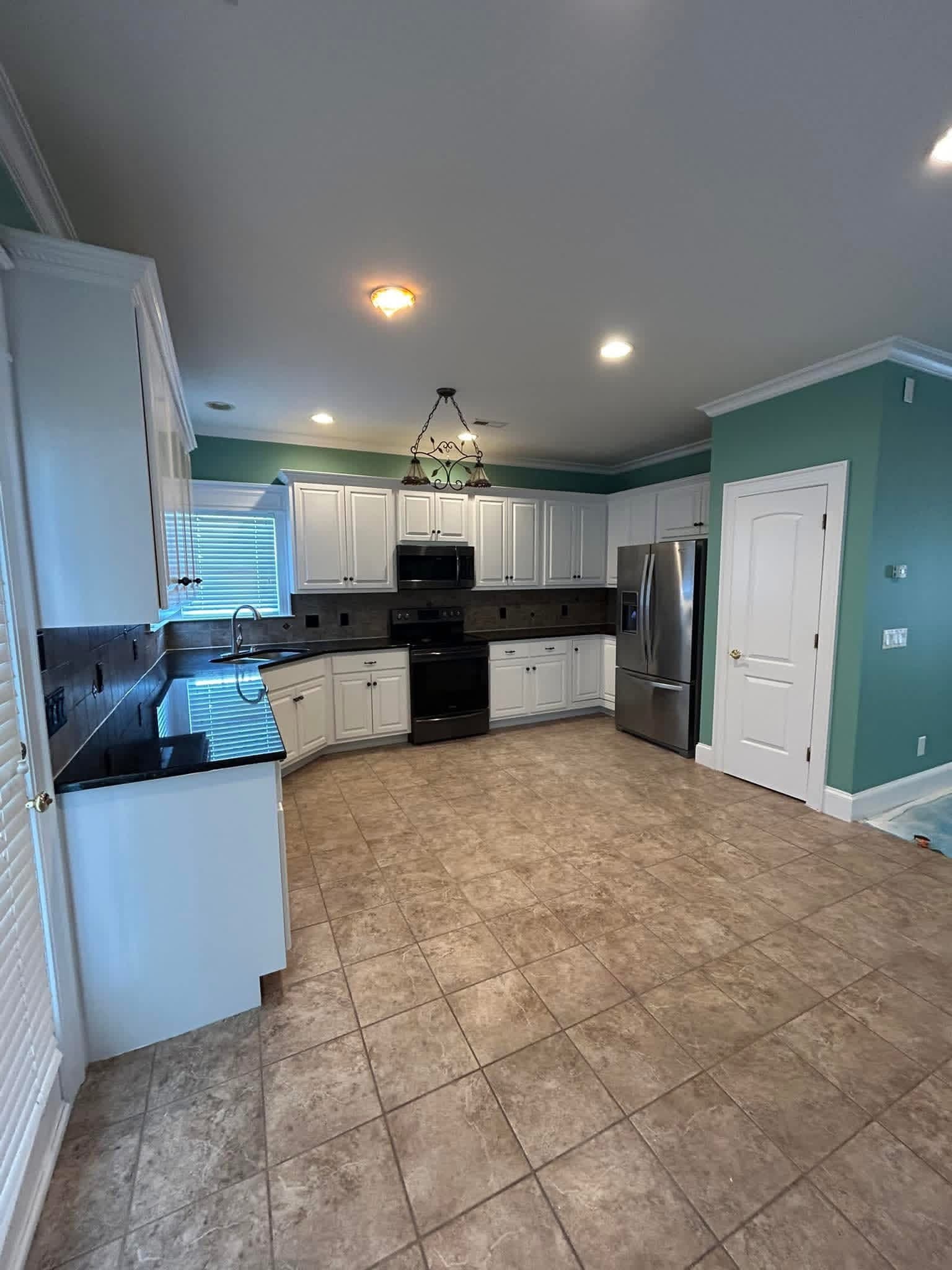 Kitchen interior with teal accent walls and white cabinet refresh by Tacho Painting LLC in Wilson NC